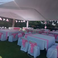 Carpa montada con mesas decoradas en rosa para evento